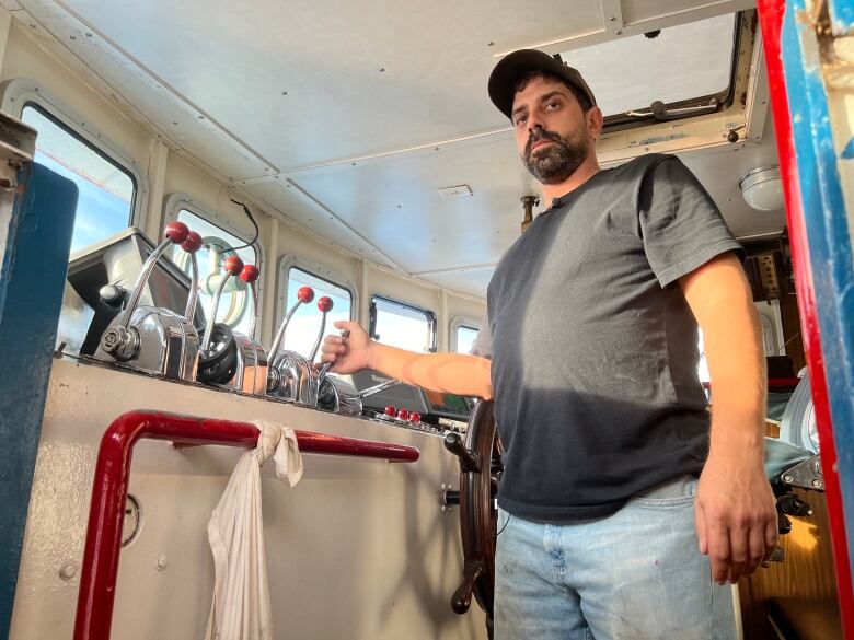 Man stands at the wheel of a boat manning the controls