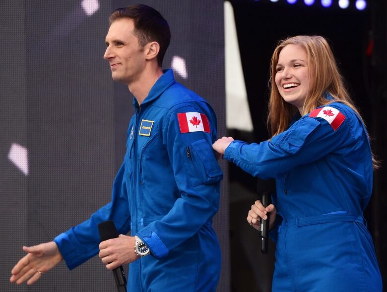 Joshua Kutryk and Jenni Gibbons are seen in their blue space jumpsuits, smiling.