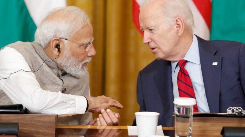 Biden and Modi chatting closely, seated at a table