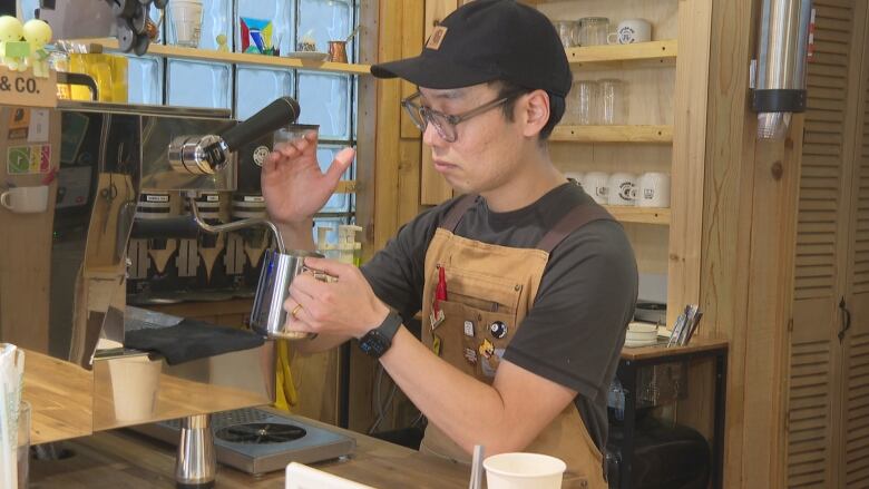 A man prepares a coffee drink in a shop.