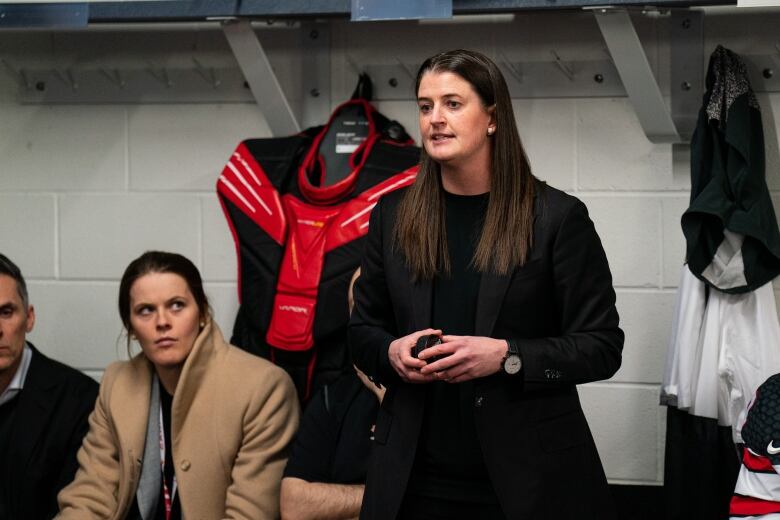 A woman is seen standing up as she speaks in a lockeroom.