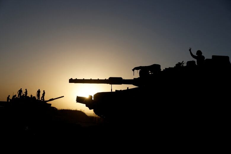 Israeli soldiers stand on a tank near Israel's border with Gaza in southern Israel.