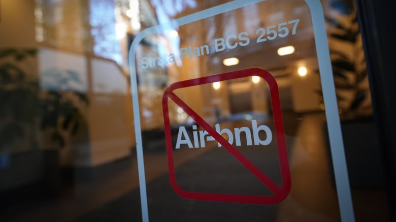 A No Airbnb sign hangs on the front of a glass apartment door.