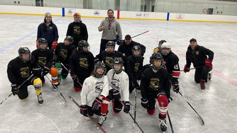 A group of hockey players kneeling on the ice for a group photo.