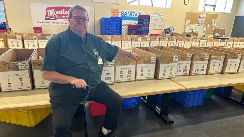 A man sitting on a large table with multiple cardboard boxes on it.