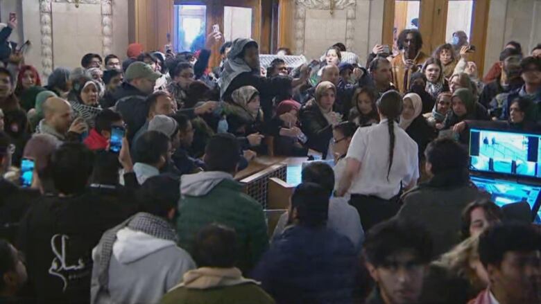 Visitors at the legislature on Monday stand waiting to receive their identification from security after question period was suspended due to protests.