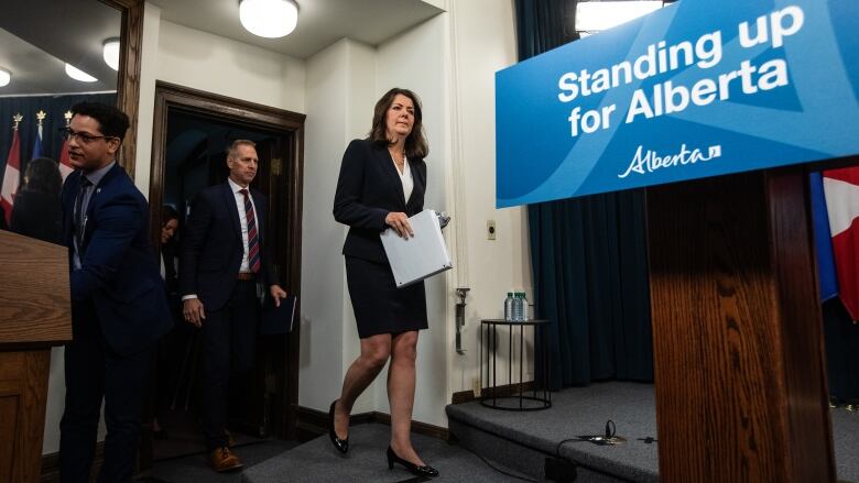 A woman in a dark suit walks to a podium.