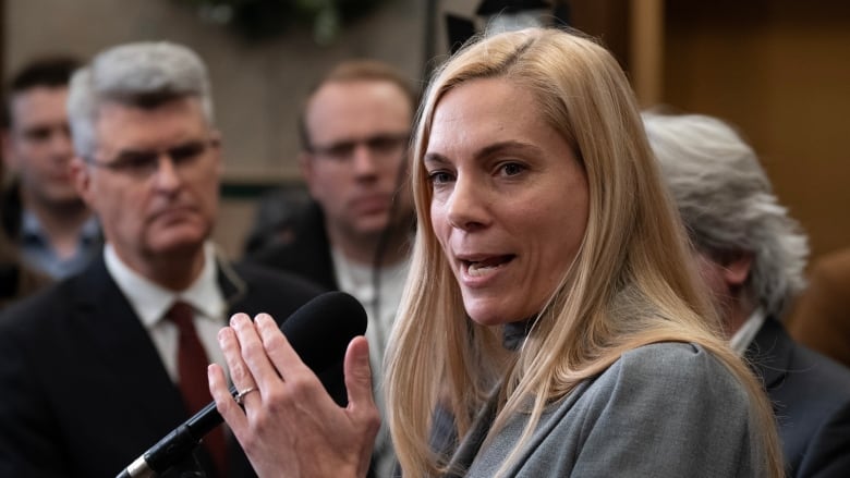 A woman in a grey blazer speaks to at a microphone outside the House of Commons.