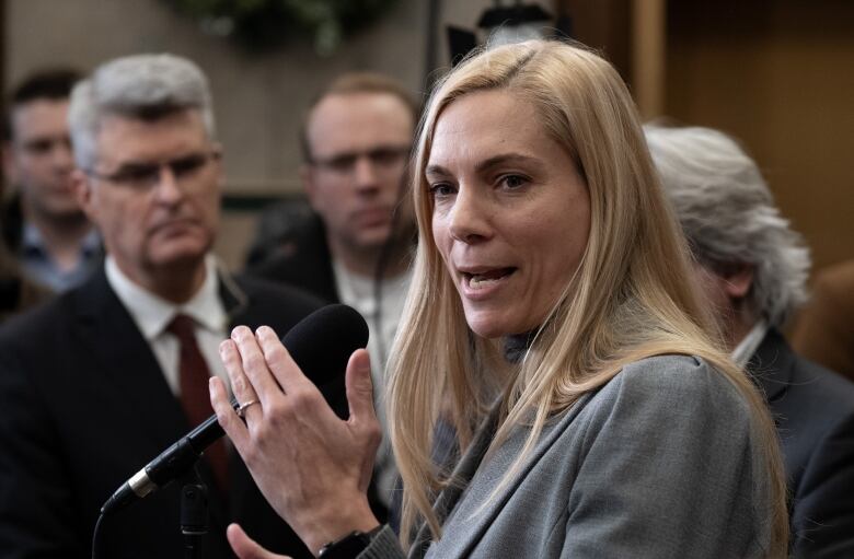 A woman in a grey blazer speaks to at a microphone outside the House of Commons.