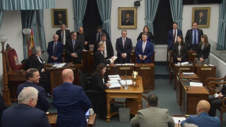 A bunch of politicians standing in a room during a vote.