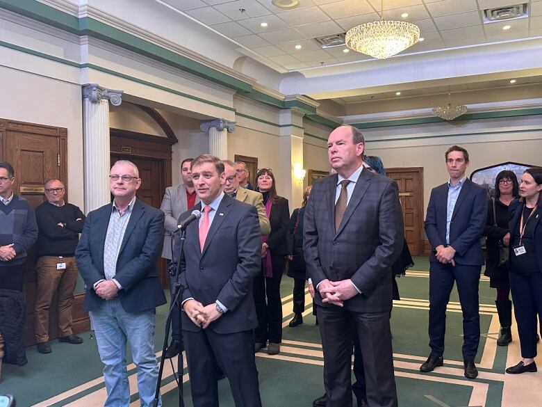 A group of people stand in front of a microphone in a government office. 