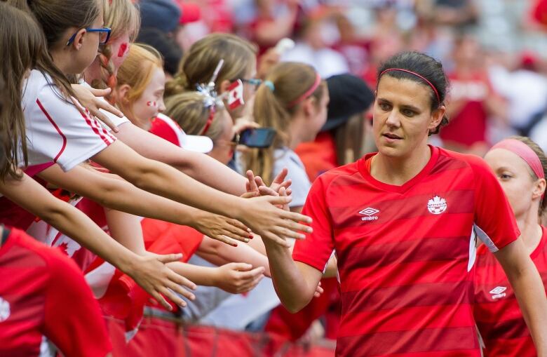 A women's soccer player high-fives fans.