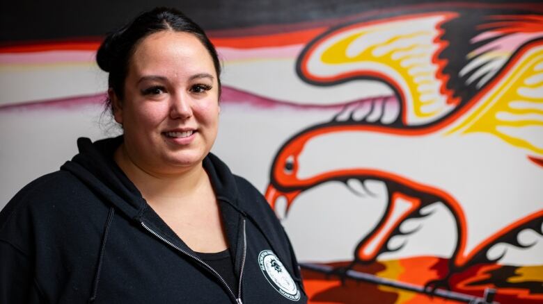 A woman smiles in front of an eagle painting.