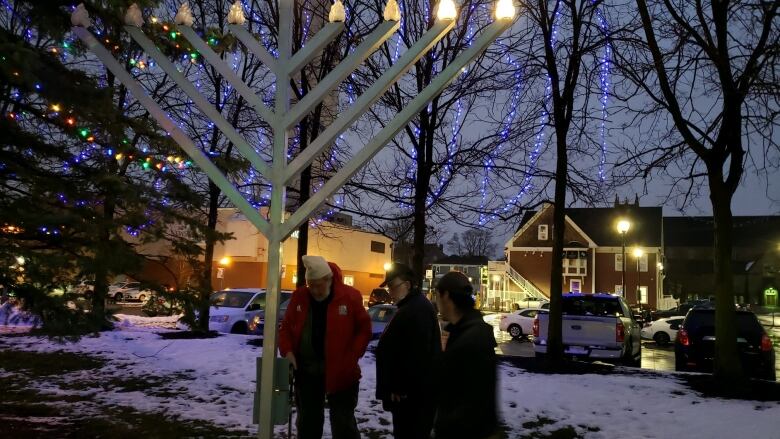 People gathered around large menorah at night time.