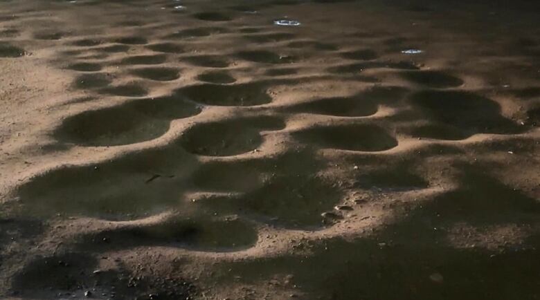 Huge potholes cover a parking lot.