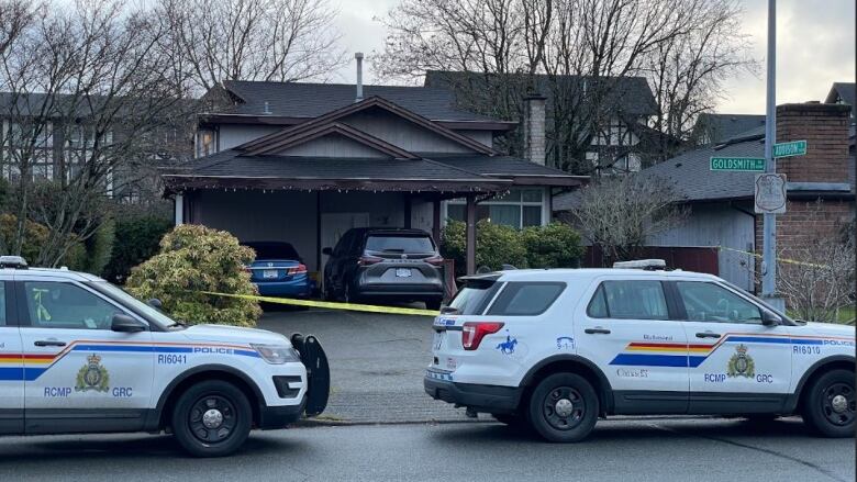 police cars parked on the street in front of a home behind police tape