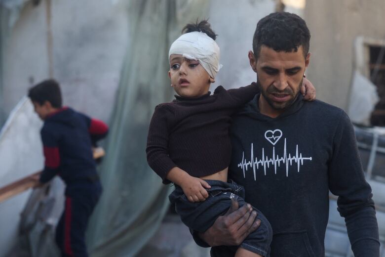 A Palestinian man carries a child injured during Israeli bombardment in Rafah.