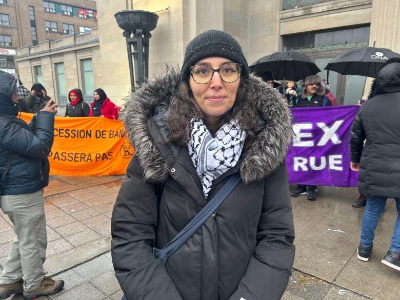 A woman stands outside in the rain.