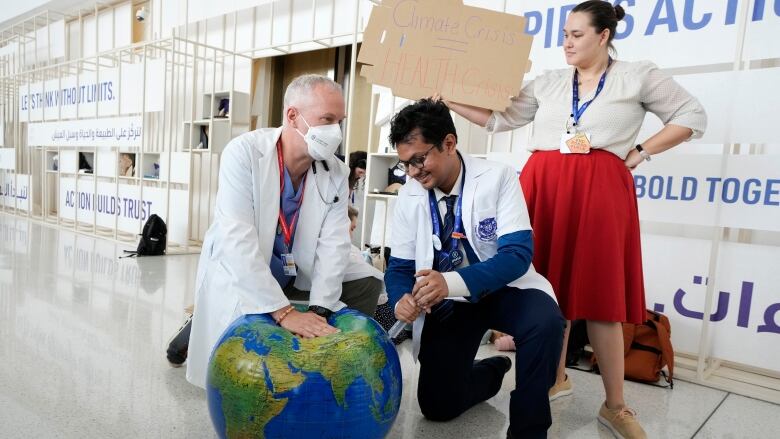 A doctor pretends to do CPR on a beachball that looks like Earth.