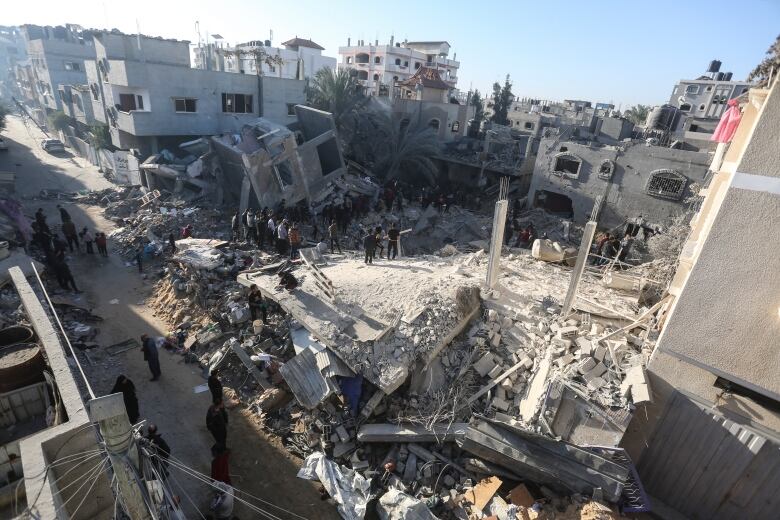 People are seen amid the rubble of a destroyed building.