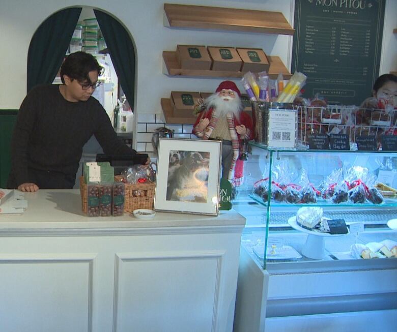 A man is pictured behind a counter of a cafe. 