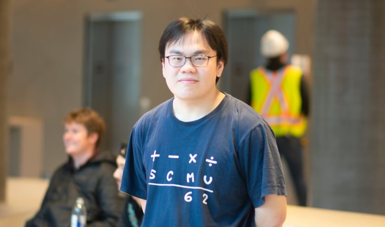 A man stands in the lobby with a construction worker in the background.