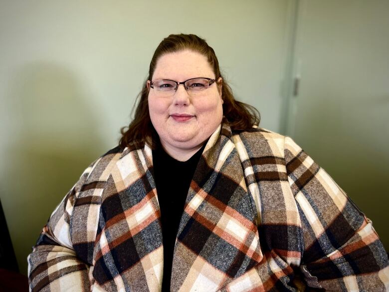 A woman in a plaid shawl smiles for the camera.