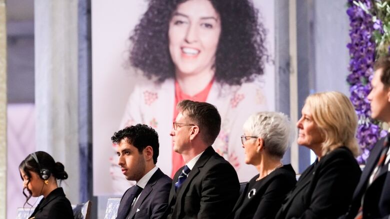 People sit in front of a photo of jailed Nobel Peace Prize winner Narges Mohammadi.