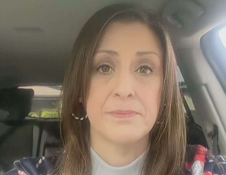 A woman is wearing hoop hearings and a white turtleneck shirt. 