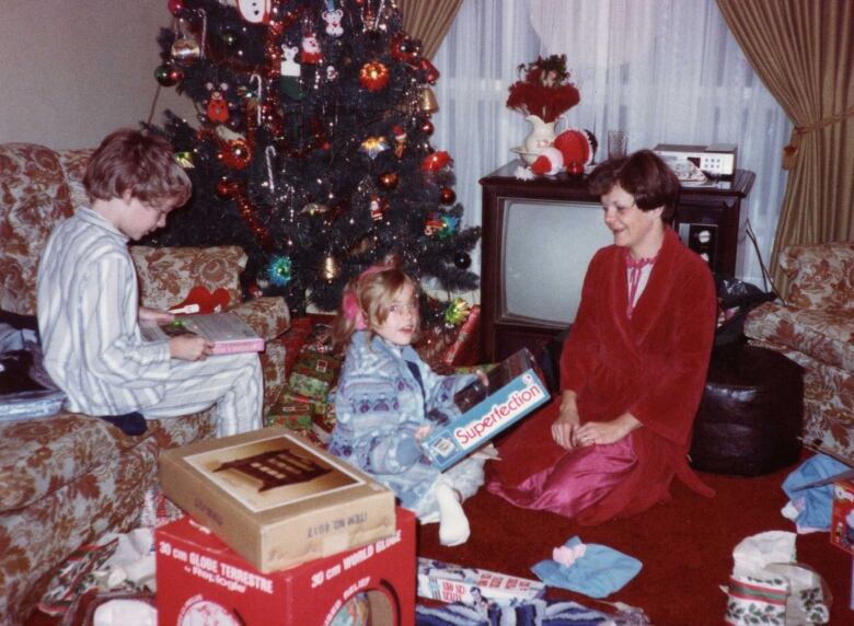 An old photograph showing a boy, a girl and their mother opening gifts on Christmas morning.