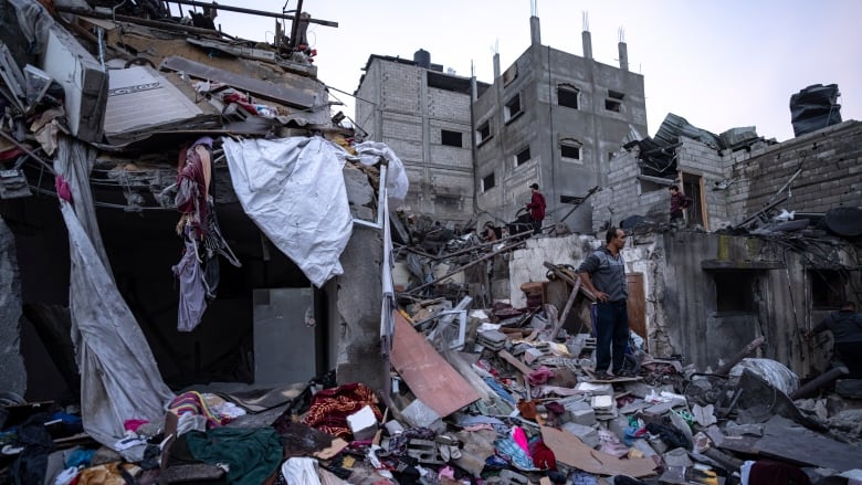 A man stands amid rubble and strewn belongings.