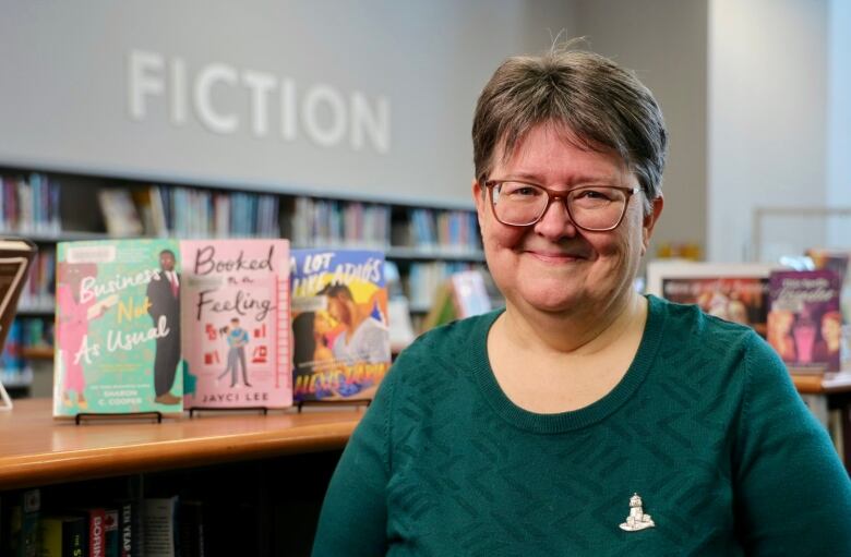 An older woman stands in front of a number of romance novels at the Woodlawn Public Library in Dartmouth.