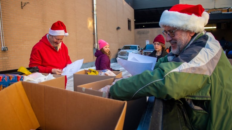 People load christmas hampers into a truckbed.