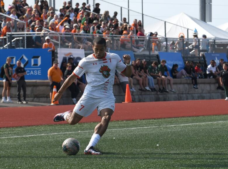 A soccer player winds up to kick the ball in front of a crowd.