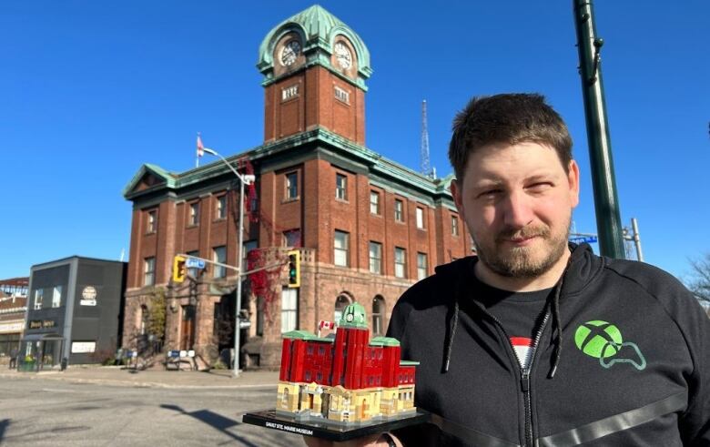 a man with a lego figure stands in front of a building in Sault Ste. Marie