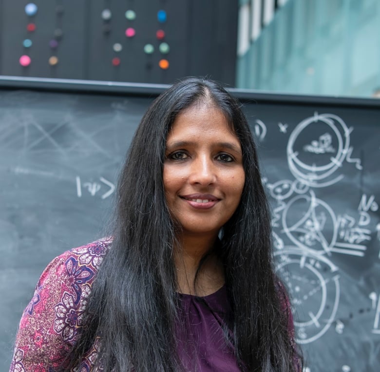 Shohini Ghose in front of a blackboard covered in equations