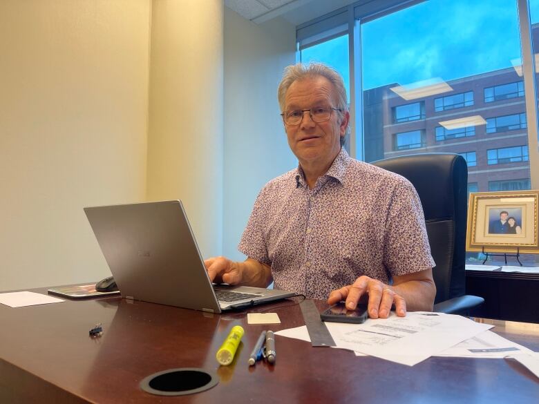 A man sits in an office on a laptop