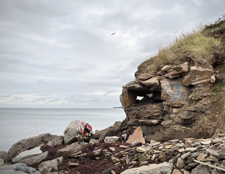 An old concrete box crumbles away as the shoreline erodes next to a harbour.