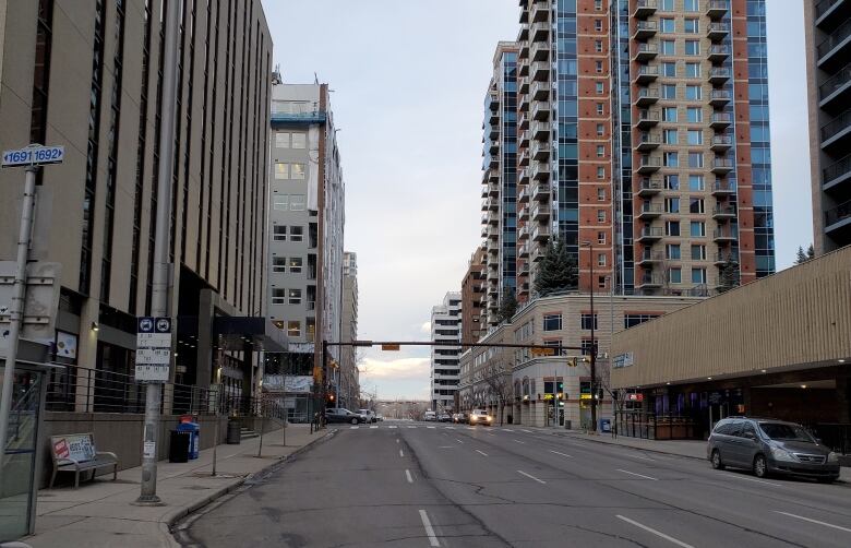 A man stands at a bus stop on an empty downtown street.