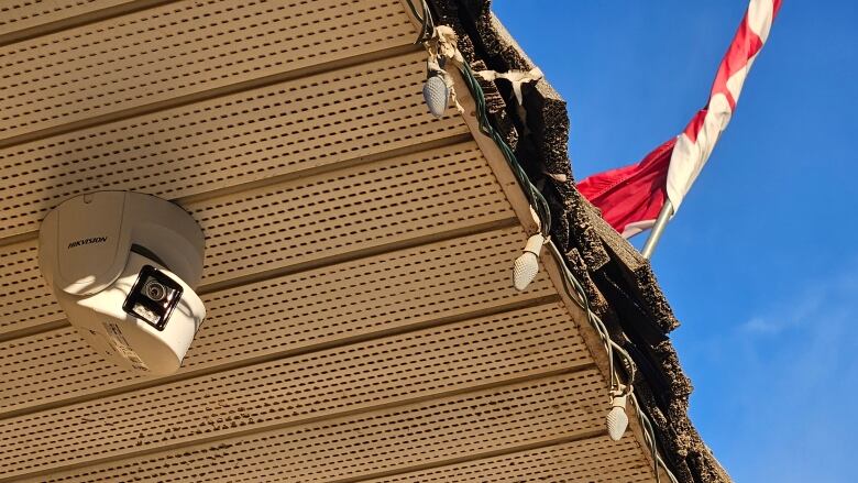 A camera is attached to the roof of a building.