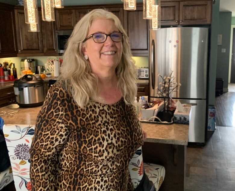 A woman in a leopard print dress stands in a kitchen.