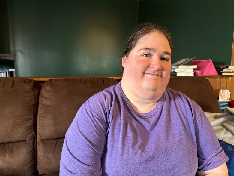 A woman sits smiling on a couch.