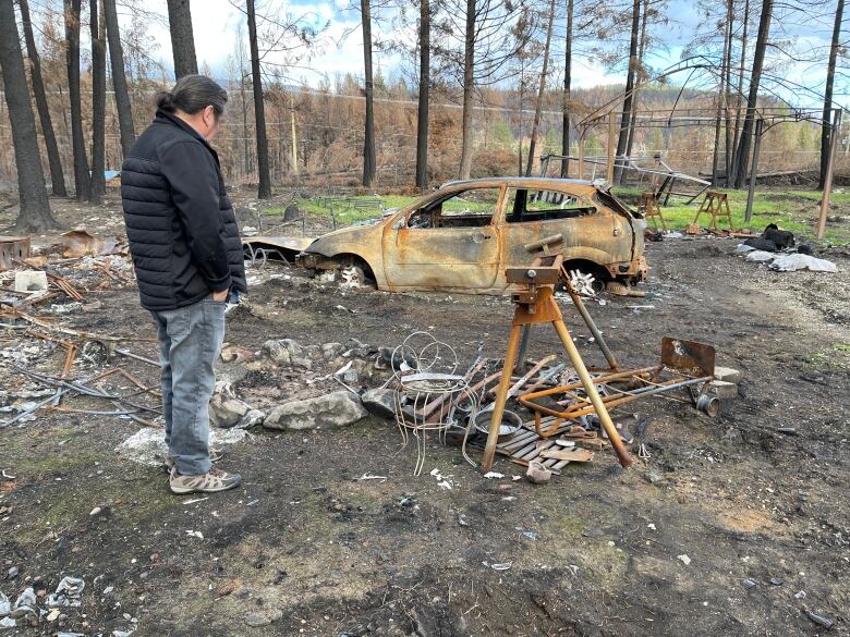 A man looks at burned objects. 