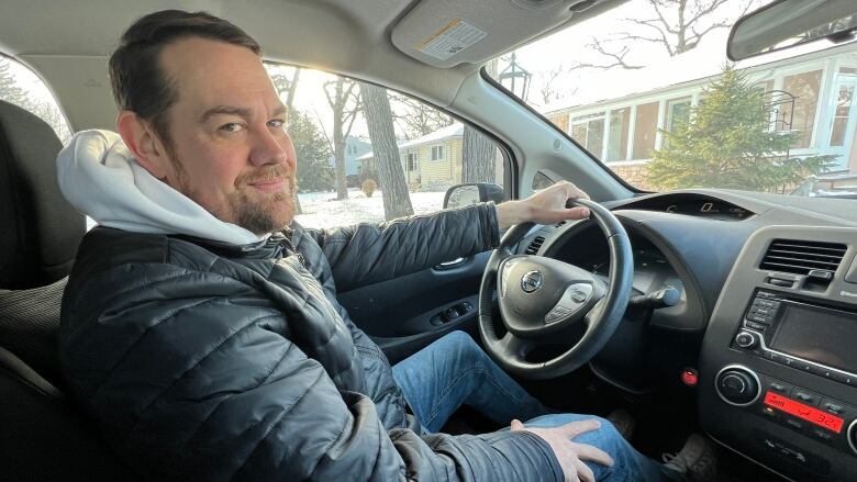 A man is pictured at the steering wheel of his car.