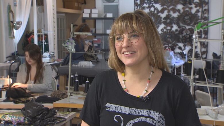 Amie Cunningham, a white woman in a black t-shirt, stands at the front of the Halifax studio of Thief & Bandit