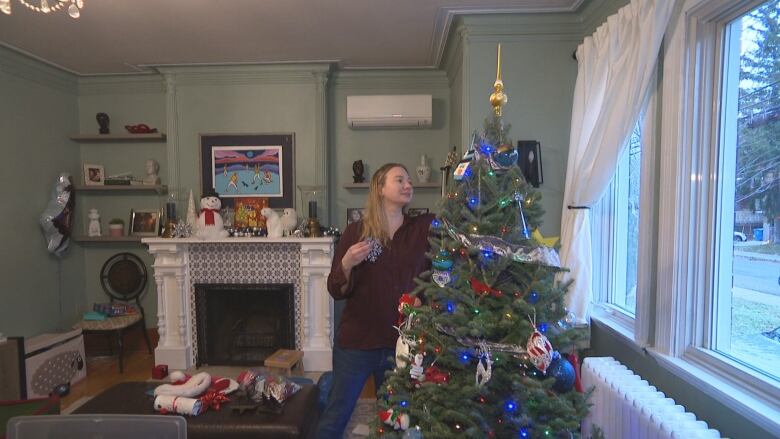 A woman decorates a Christmas tree.