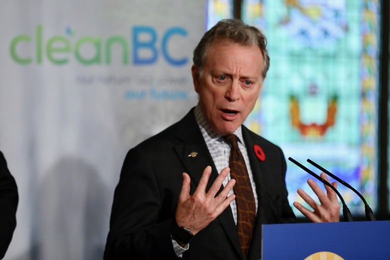 A man gestures while speaking at a podium, with a banner marked 'CleanBC' behind him.