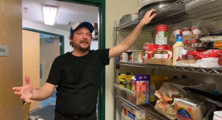 Man leaning against a shelf .