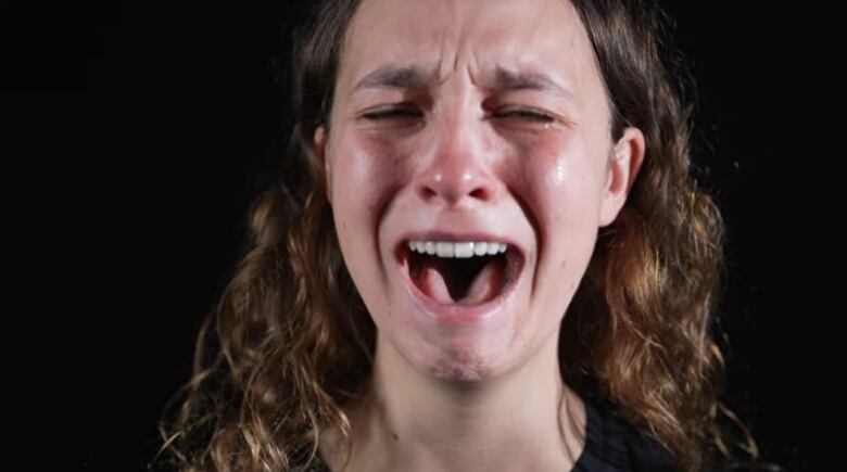 A woman is seen crying while singing.