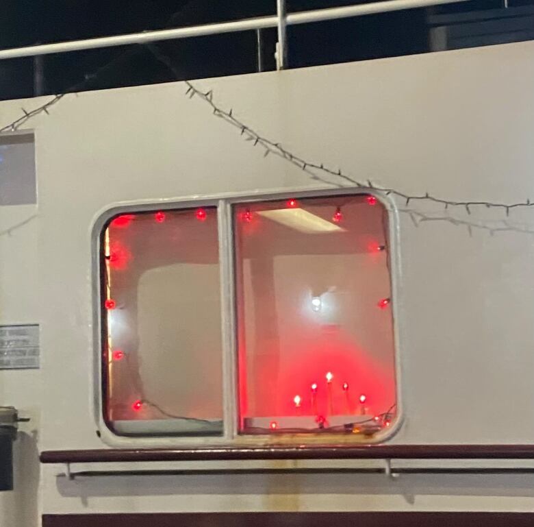 A ferry window features glowing red candle lights on display.